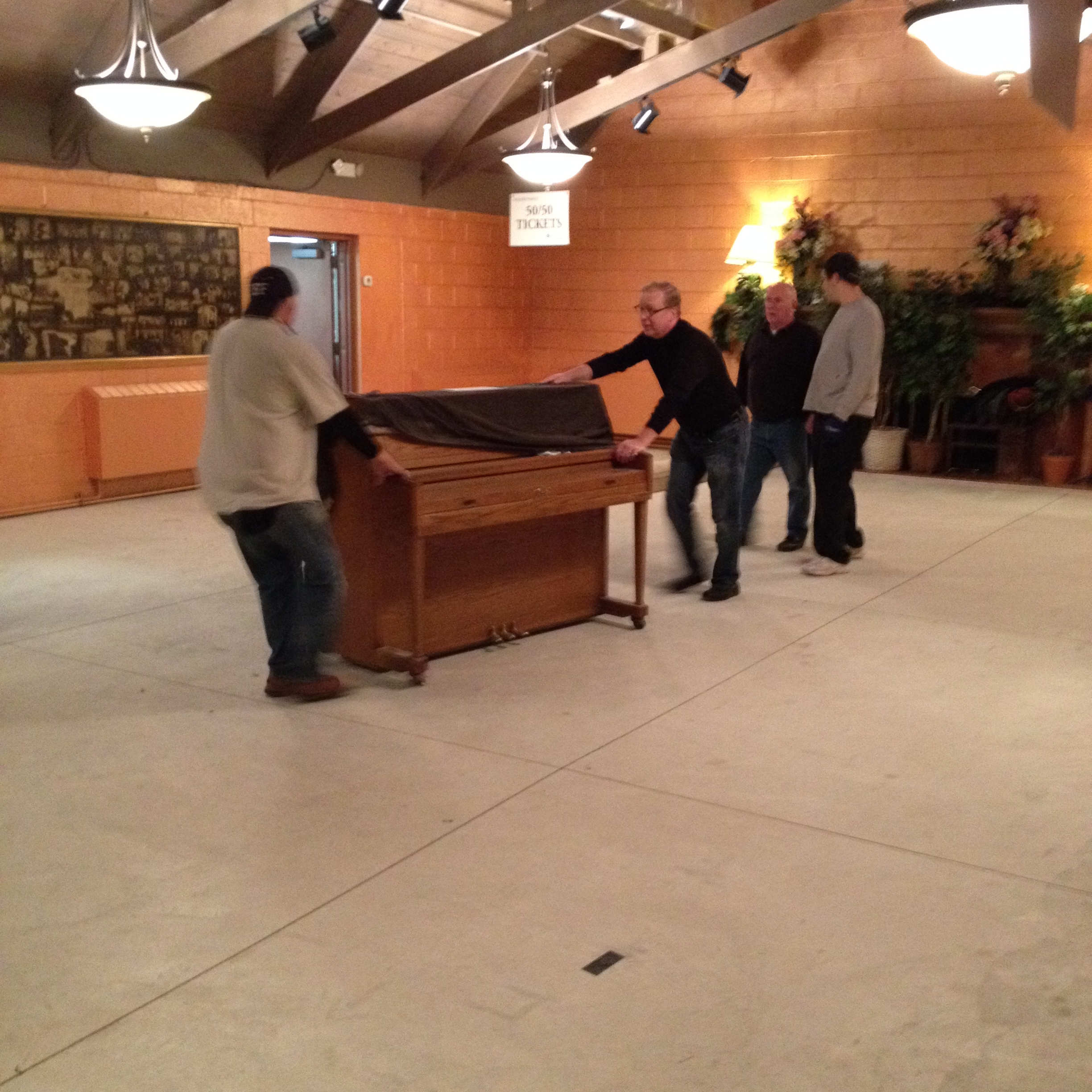 Pat Denyer and Richard Moore move the piano while Chris Boudreau and Steve Gautreau watch.